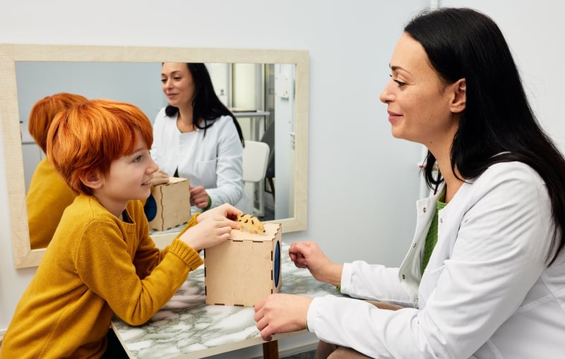 Female psychologist using ABA therapy techniques with a child patient.